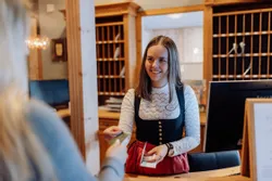 Hotel receptionist in traditional attire handing keycard to guest at front desk